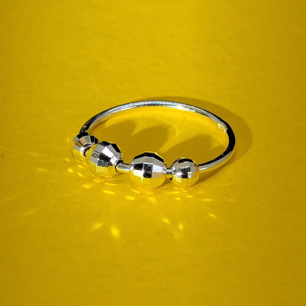 Disco sterling silver fidget ring with four spinning beads, handmade in Nottingham