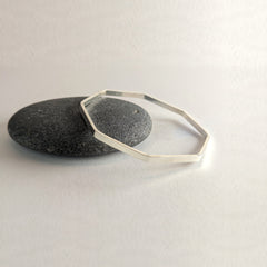'Octangle' Sterling Silver Slim Octagonal Shaped Polished Bangle on a pebble, view 3