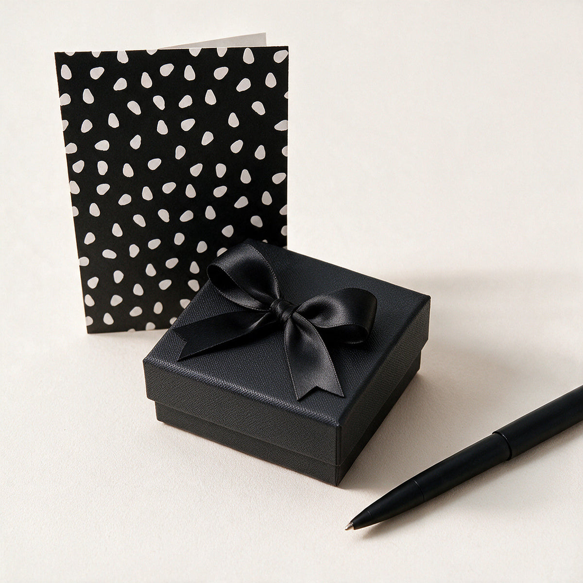 Gift wrap and handwritten card: black box with satin bow, dotted card and pen