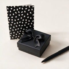 Gift wrap and handwritten card: black box with satin bow, dotted card and pen, view 1